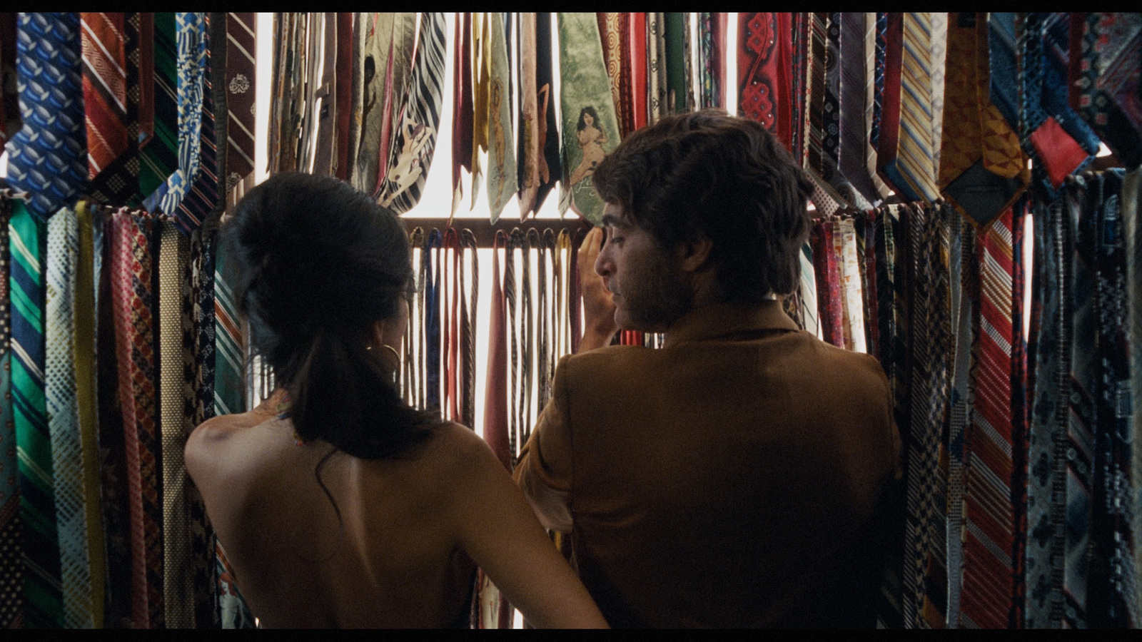 a man and a woman looking at ties in a store