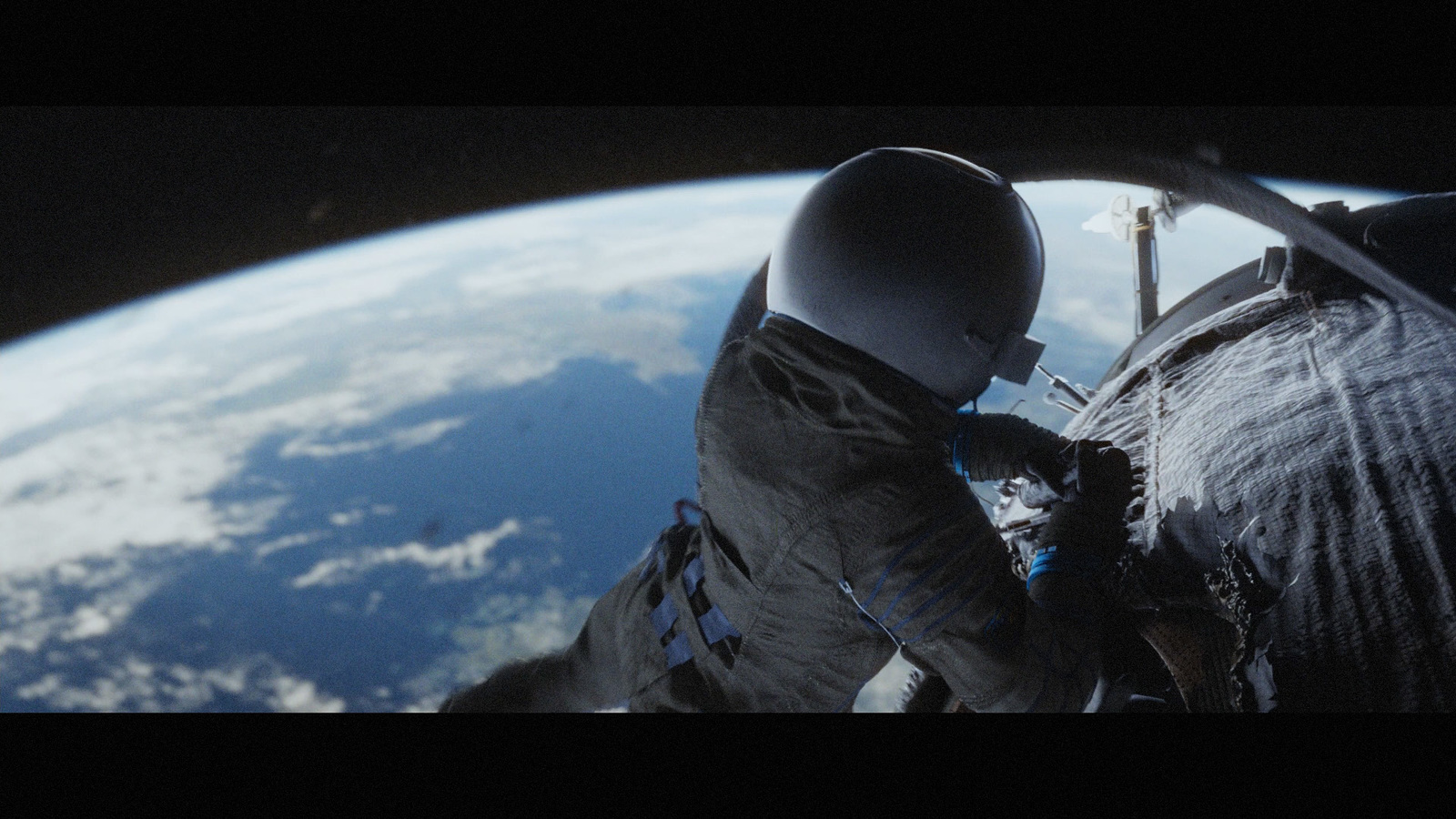 a man in a space suit standing in front of the earth