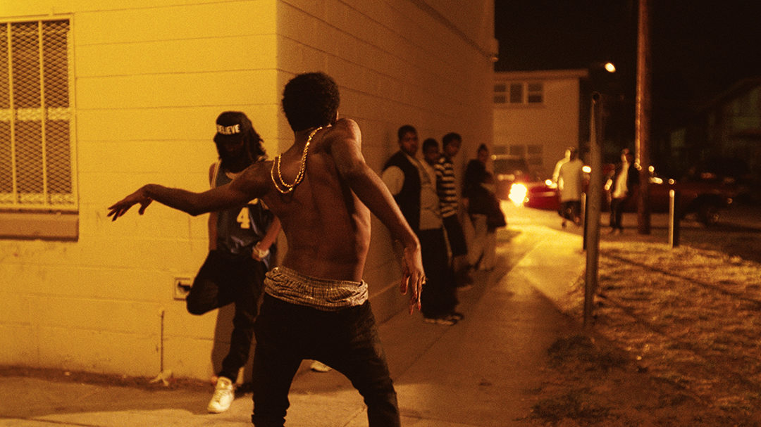 a shirtless man riding a skateboard down a sidewalk