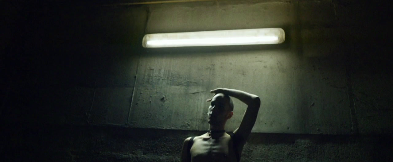 a man standing in a dark room with his hands behind his head