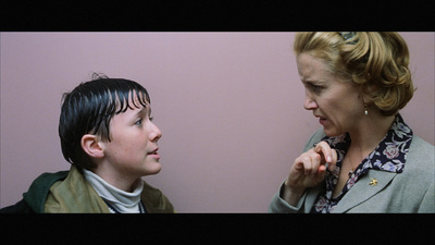 a woman standing next to a boy who is brushing his teeth