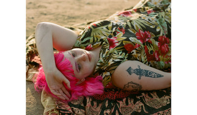 a woman with pink hair laying on a blanket