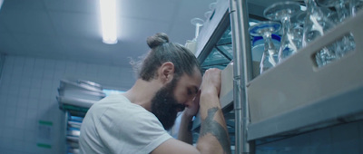 a man in a white t - shirt is looking into a refrigerator