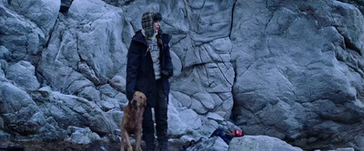 a man standing next to a dog on a rocky hillside