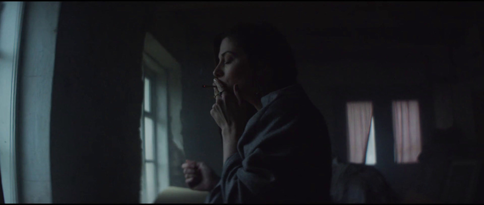 a woman standing in a dark room talking on a cell phone