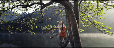 a woman sitting on a tree branch next to a lake