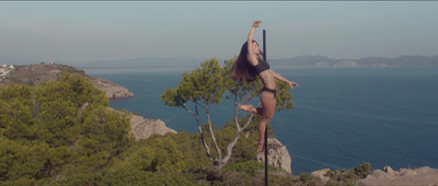 a woman standing on a pole on top of a cliff