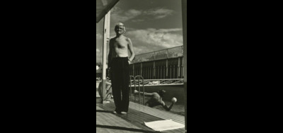 a black and white photo of a man standing on a dock