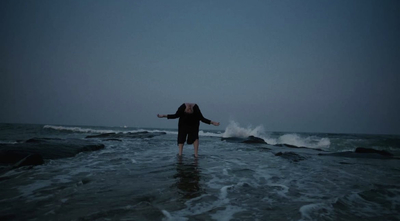 a woman standing in the ocean with her arms outstretched