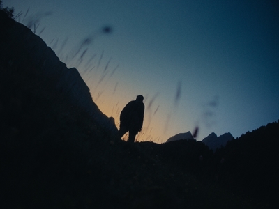 a silhouette of a person standing on a hill