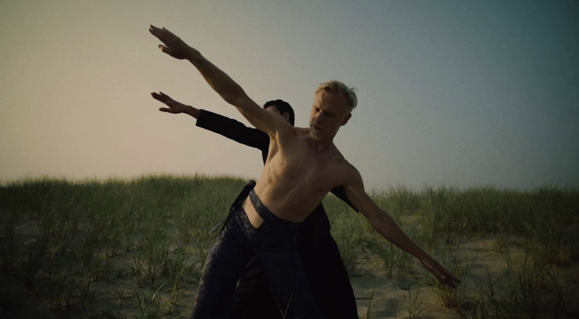 a couple of men standing on top of a sandy beach