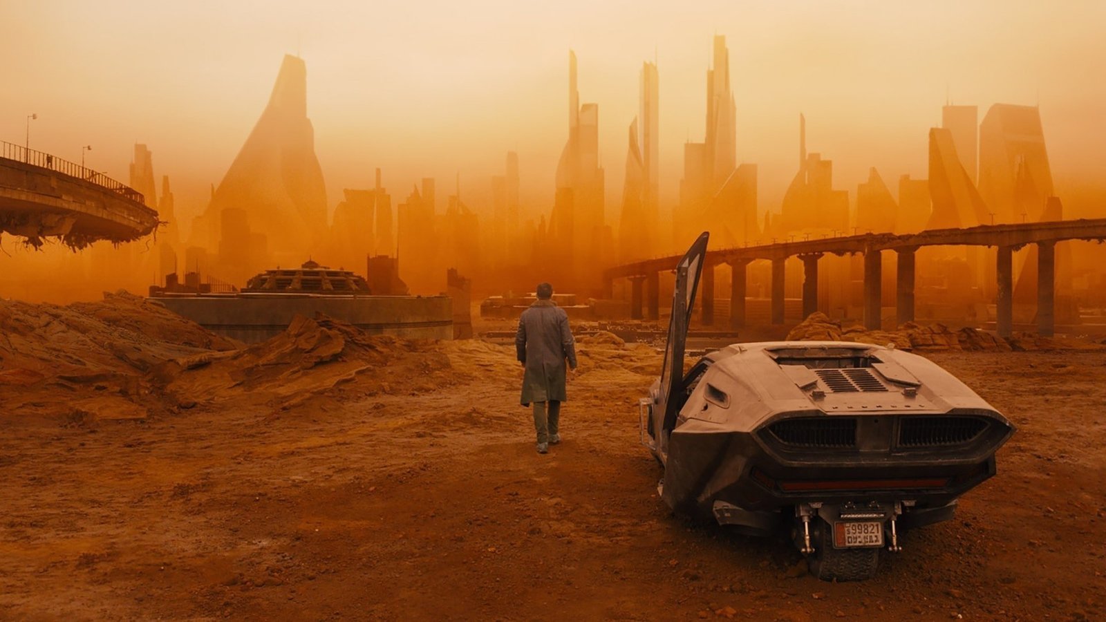 a man standing next to a car on a dirt field