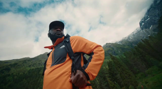 a man with a backpack standing in front of a mountain