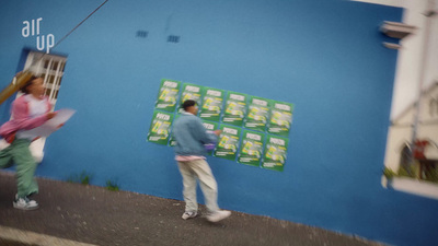 a couple of people walking past a blue wall