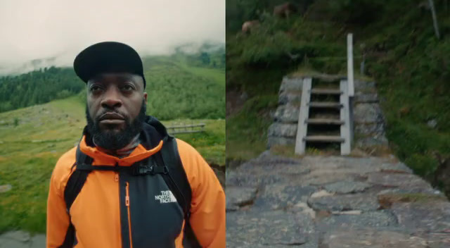 a man in an orange jacket standing in front of a mountain