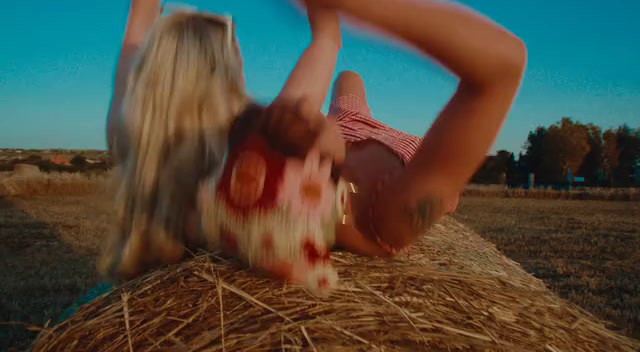 a woman laying on top of a pile of hay