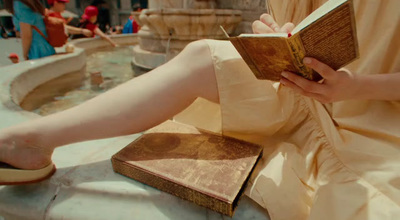 a woman sitting on a fountain reading a book