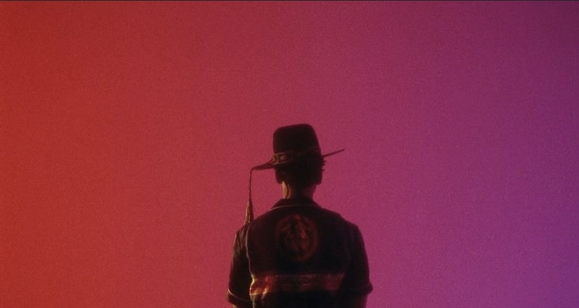 a silhouette of a man with a hat and a gun