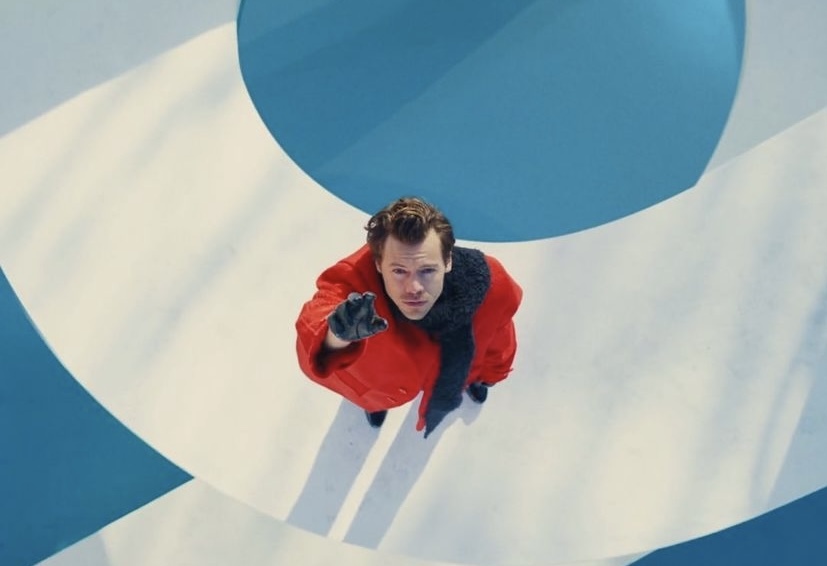 a man in a red jacket standing in front of a blue and white wall