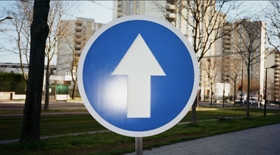 a blue and white sign with an arrow pointing right