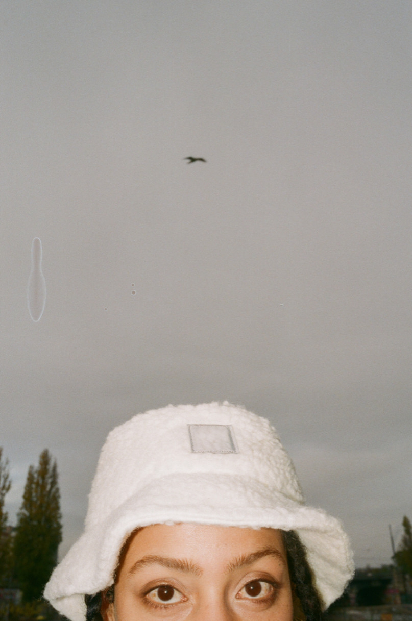 a woman wearing a white hat with a bird flying overhead