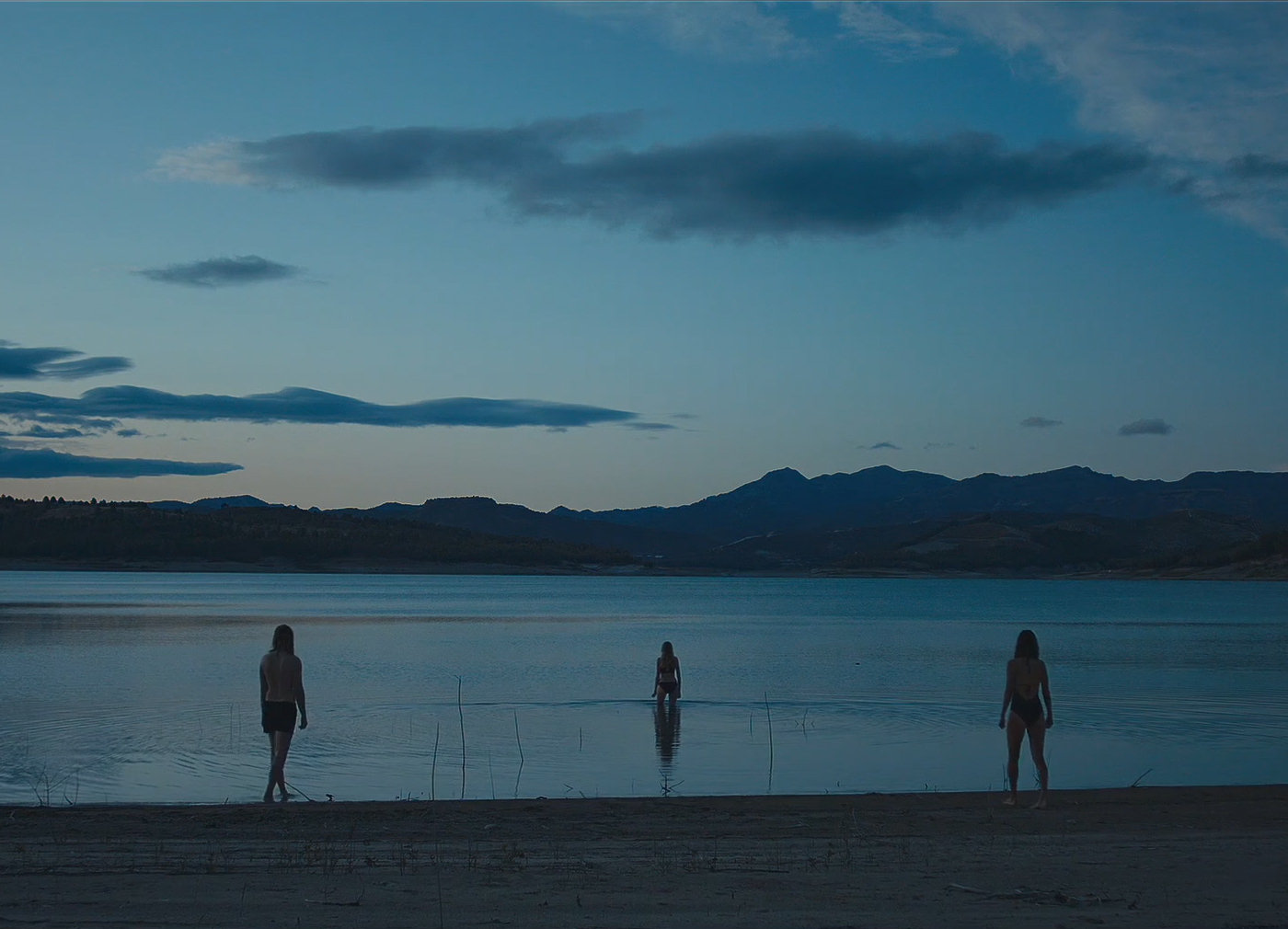 a group of people standing on top of a beach next to a body of water