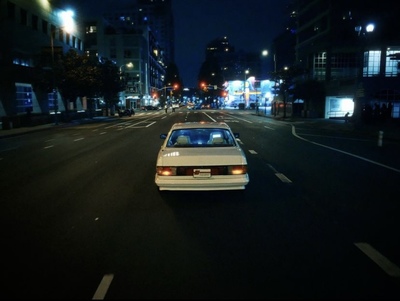 a white car driving down a city street at night