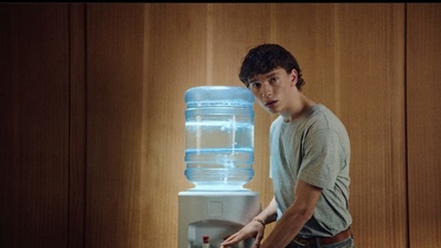 a young man standing in front of a water dispenser