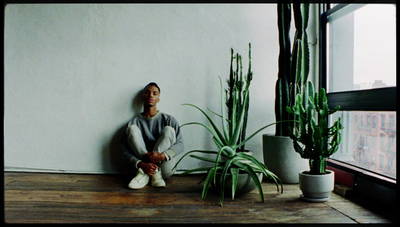 a man sitting on the floor next to a plant