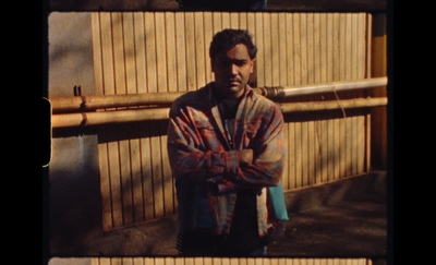 a man standing in front of a wooden fence