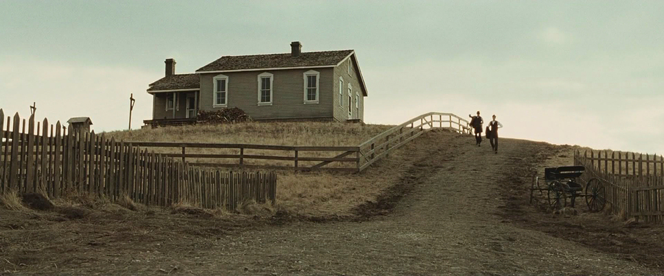 a house on a hill with a fence and a person standing in front of it