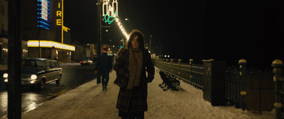 a woman walking down a snow covered sidewalk