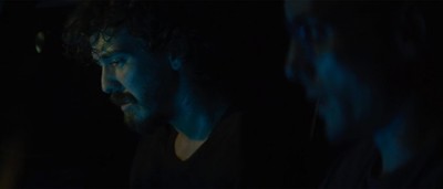 a man with a beard looking at something in the dark