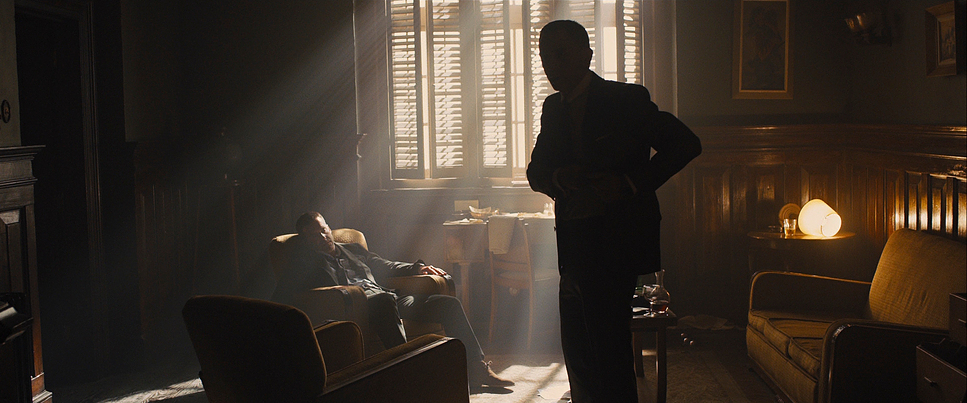 a man standing in a living room next to a chair