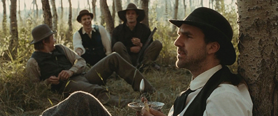 a group of men sitting next to each other in the woods