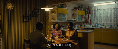 a group of people sitting around a table in a kitchen