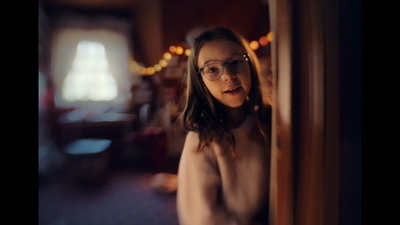 a woman wearing glasses standing in front of a door