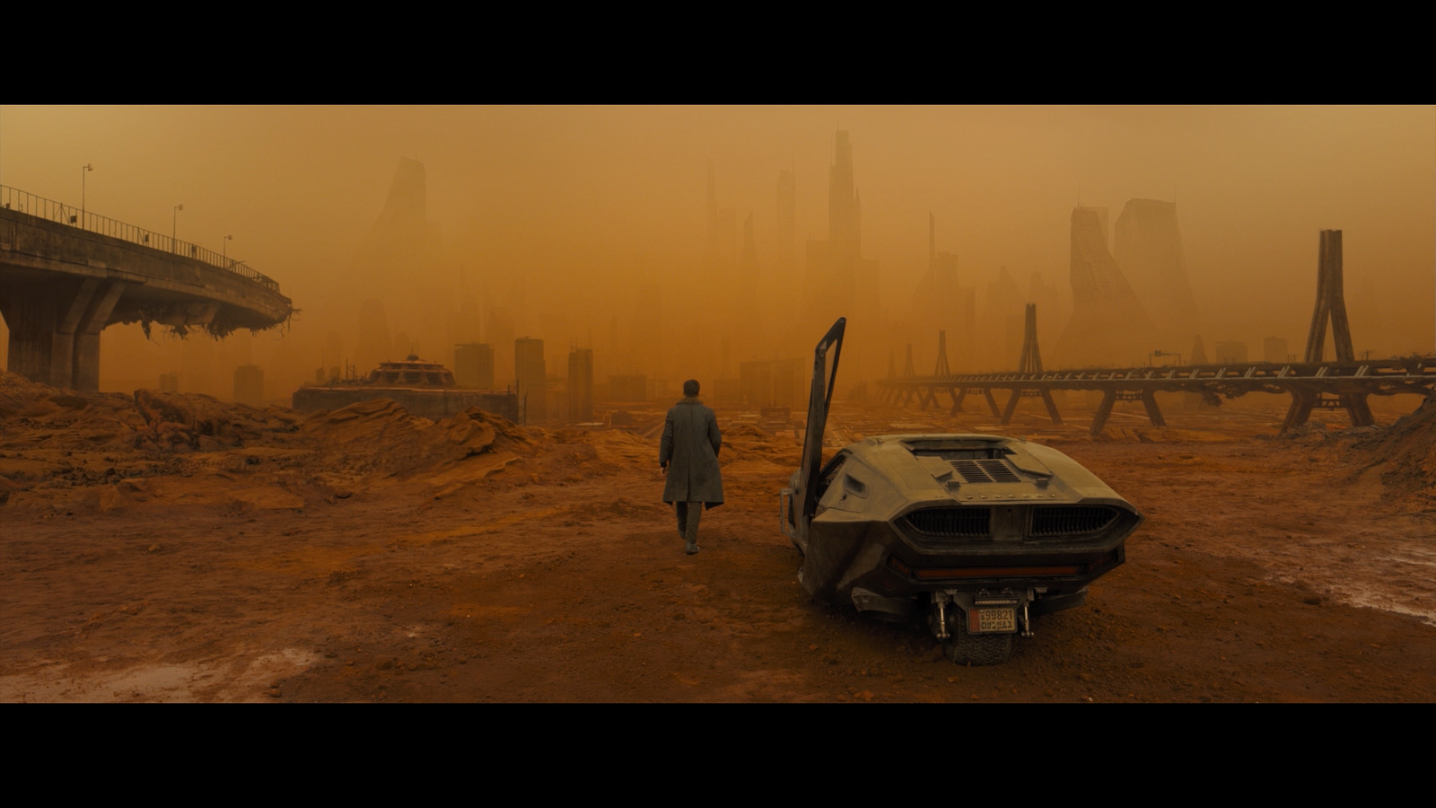 a man standing next to a car on a dirt field