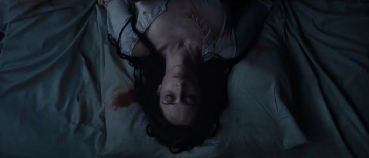 a woman laying on a bed covered in blood