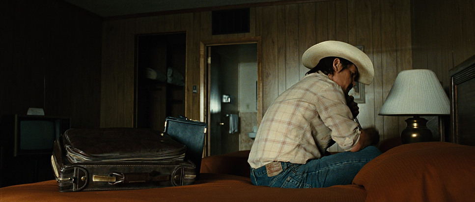 a man in a cowboy hat sitting on a bed