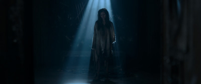 a woman standing in a dark room with a light shining on her