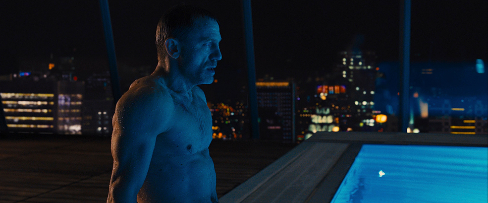 a man standing next to a swimming pool at night