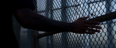 a person holding a cigarette in front of a chain link fence