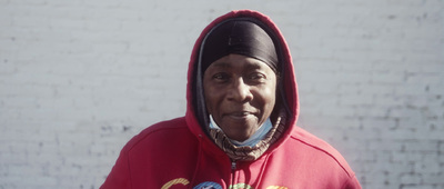 a woman in a red hoodie is standing in front of a brick wall