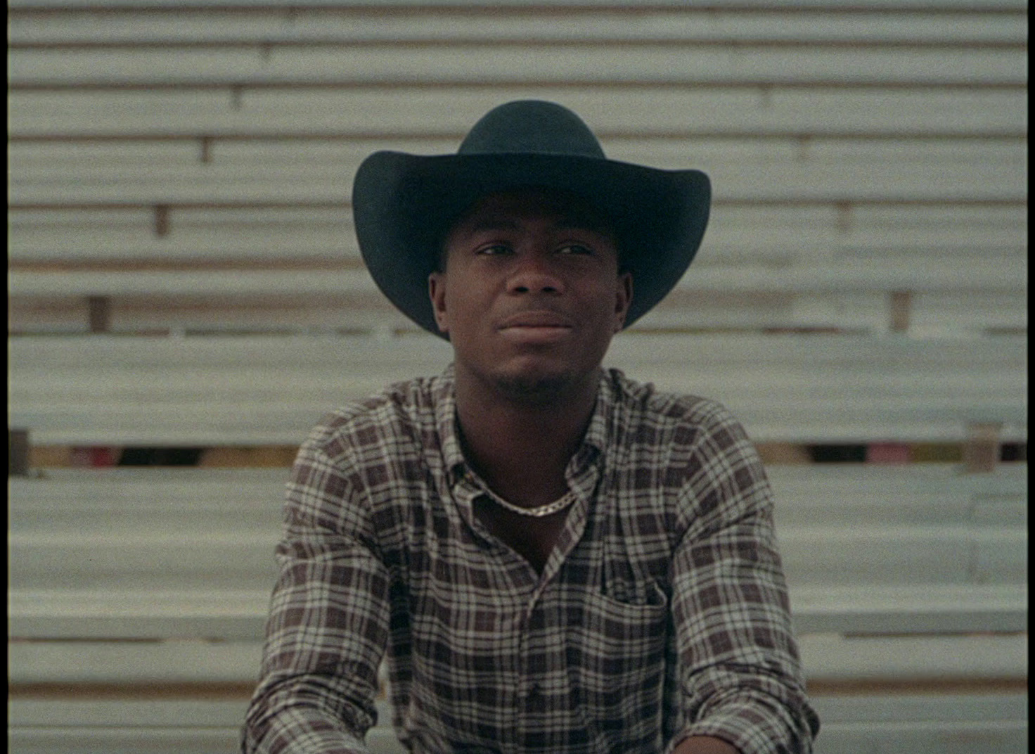 a man wearing a cowboy hat sitting in a bleachers