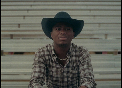 a man wearing a cowboy hat sitting in a bleachers