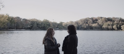 a couple of women standing next to a lake