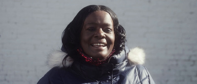 a woman in a blue jacket smiles at the camera