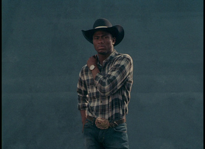 a man wearing a cowboy hat standing in front of a wall