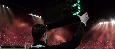 a man holding up a score board in front of a crowd